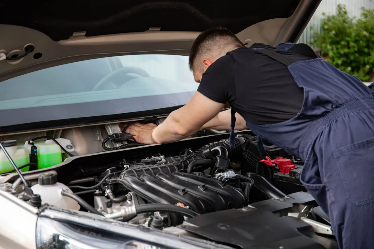 Mechanik pracuje pod otevřenou kapotou auta